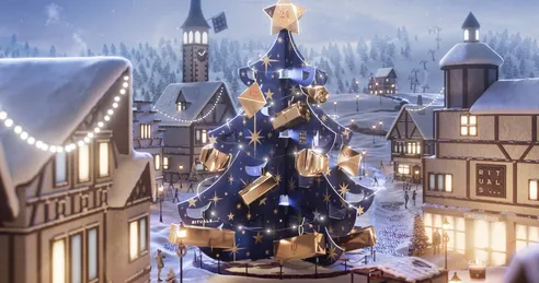A christmas tree decorated with presents in the middle of a winter town.